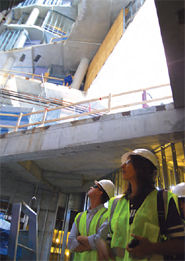 Photo of two construction workers in hard hats and vests at a site