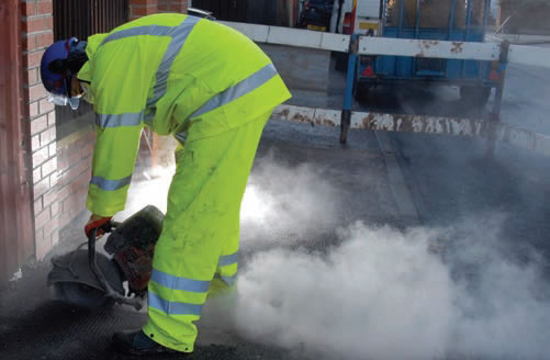 photo of man cutting concrete kicking up a lot of dust