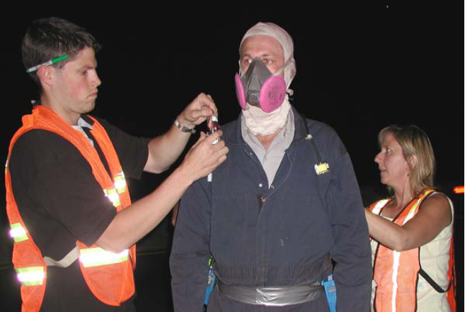 Photo of a worker putting on PPE appropriate for abrasive blasting work.