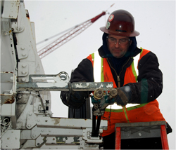 Photo of a man working while it is snowing.