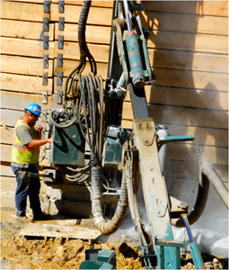 Man standing by equipment with dust or fumes.