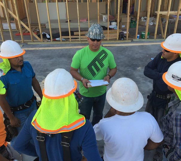 Men listening to a trainer at a worksite