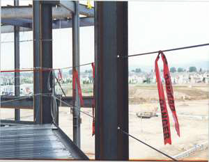 Construction site with beams, strung with two cables as guard rails and flags.