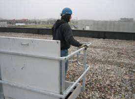 Photo of a man standing at a swing gate that has a guardrail and grab bars on the rooftop