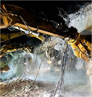 This is a picture of concrete Bridge Demolition with worker safely in enclosed vehicle
