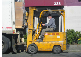 man driving a forklift, lifting a pallet fron a truck