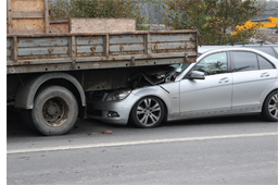 Picture of a car shoved under the rear end of a large truck